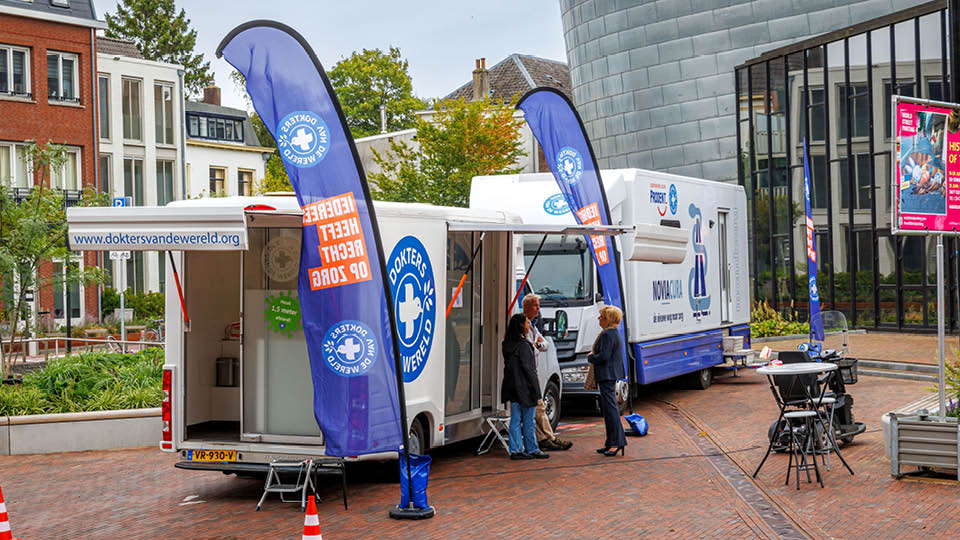 Tiel, 17 september 2025 Mondzorgkaravaan op het Agnietenplein. Wethouder Carla Kreuk krijgt informatie bij de tandarts behandeling van patient Linda Gebel. Foto Jan Bouwhuis.